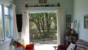 A cozy room with a bed, a chair, a small table, and a window with curtains. - Gorgeous Character Bach (Punakaiki)