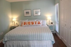 A bedroom with a bed, two bedside tables, a nightstand, and a door. - Firethorn 321- 2 bedroom 2 bath enjoy a fabulous direct beach front view from this 2nd story walk up (Sarasota)