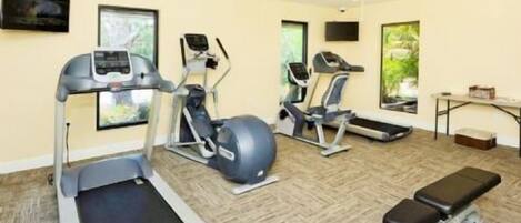 Un gimnasio con cintas de correr, una elíptica, una bicicleta estática y una máquina de remo.