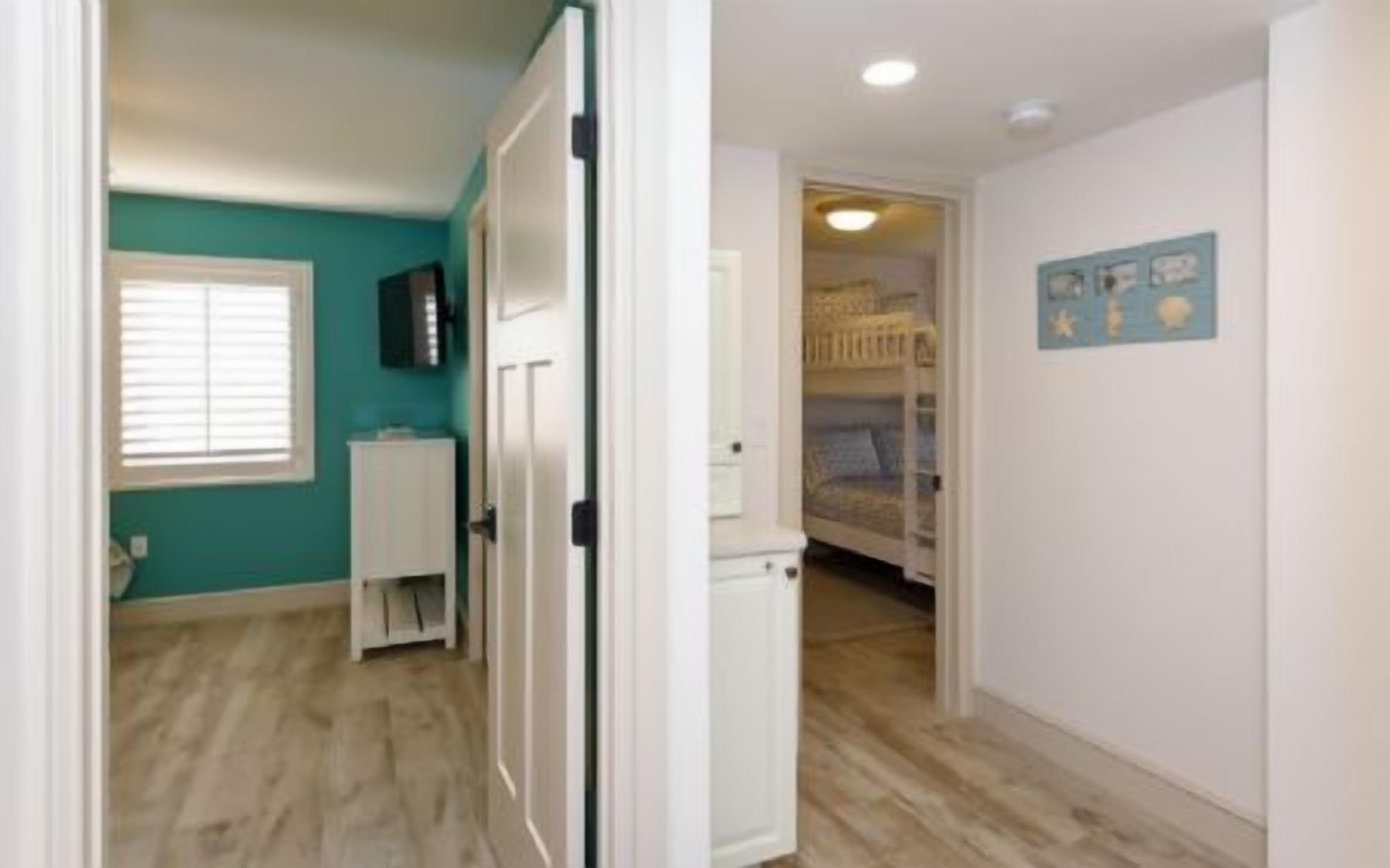 A room with teal walls, a white door, and a bed with a blue headboard.