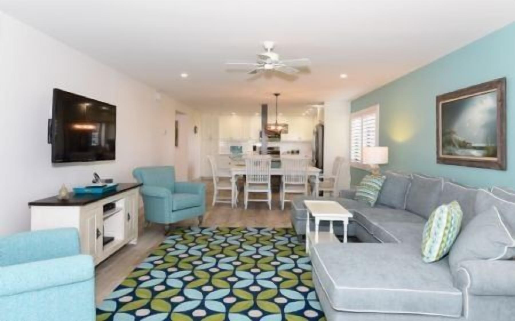 A modern living room with a grey sofa, a blue armchair, and a patterned rug.