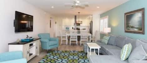 A modern living room with a grey sofa, a blue armchair, and a patterned rug.