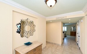 A hallway with a decorative wall mirror, a wooden cabinet, and a tiled floor.