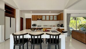 Een moderne keuken met een centraal eiland, houten kasten en een eethoek met drie barkrukken.