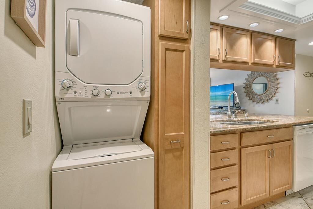 A compact kitchen with wooden cabinets, a built-in dishwasher, and a large window above the sink.