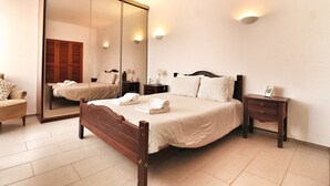 A bedroom with a large mirror, a wooden bed, a bedside table, and a chair. - Portuguese house with a large private pool and very close to the beach. (Carvoeiro)