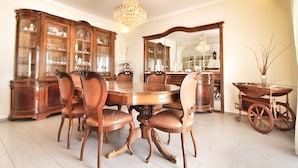 A dining room with a wooden table and chairs, a chandelier, and a mirror. - Portuguese house with a large private pool and very close to the beach. (Carvoeiro)