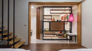 Una habitación de hotel moderna con escalera de madera, un escritorio de madera, una cama y una lámpara colgante rosa.