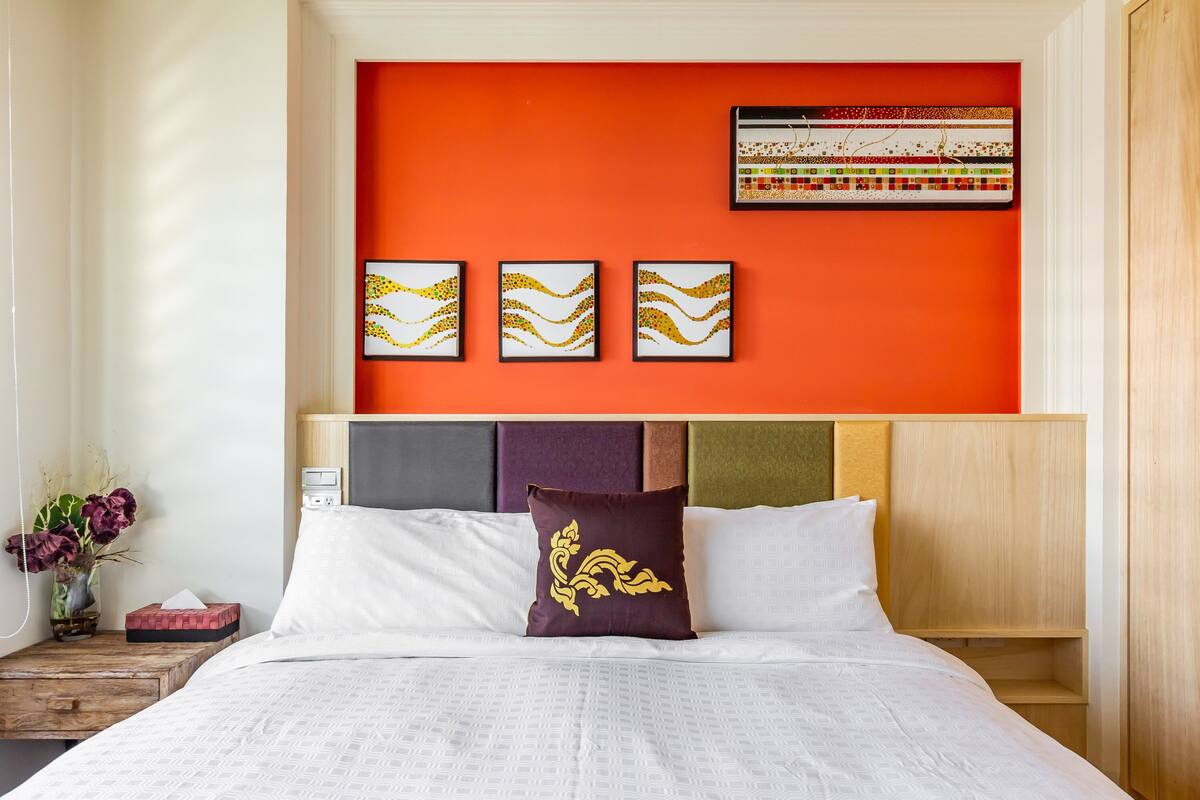Una habitación de hotel con una cama grande, una mesita de noche con un florero y una pared con tres obras de arte enmarcadas.