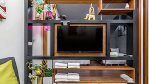 Una sala de estar moderna con un televisor de pantalla plana, estanterías de madera y una planta.