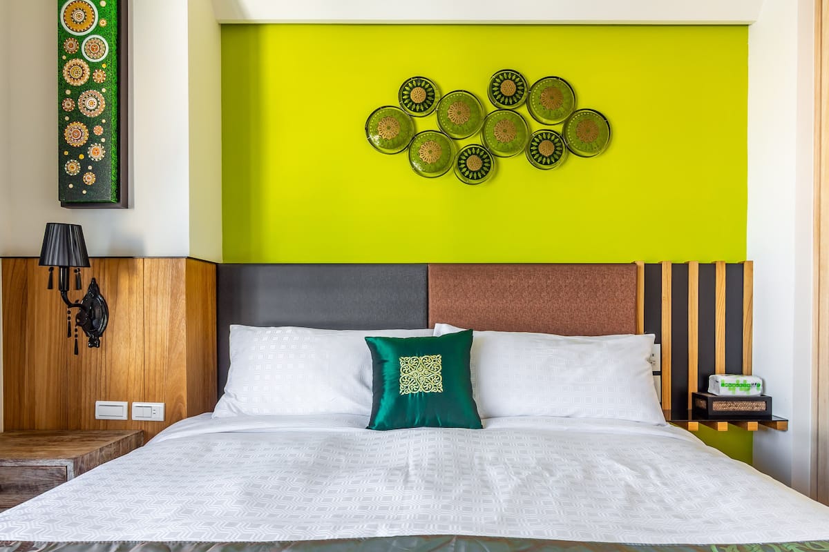 Una habitación de hotel con una cama, una pared verde y una composición decorativa de platos.