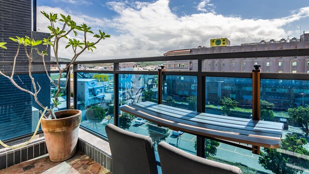 Un balcón con planta en maceta, un banco y vista panorámica de la ciudad.