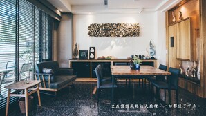 Un área de comedor moderna con una mesa de madera, sillas y un sofá. Hay un adorno en la pared sobre la mesa y un mueble de madera con objetos decorativos a la derecha.