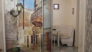 Quarto com uma grande porta deslizante com uma pintura de paisagem urbana, tapete estampado e sofá branco.