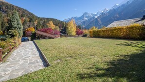A stone pathway leading to a building with a red roof, surrounded by autumn-colored trees and snow-capped mountains. - Apt Beauregard1 Family Duplex Parking & near ski, Les Houches (Chamonix), France (Les Houches (Chamonix))