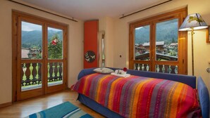 A bedroom with a bed, a window, a lamp, and a view of the outside. - Apt Beauregard1 Family Duplex Parking & near ski, Les Houches (Chamonix), France (Les Houches (Chamonix))