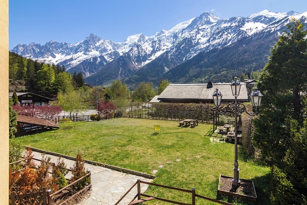A mountain view with a grassy area, benches, and a lamp post.