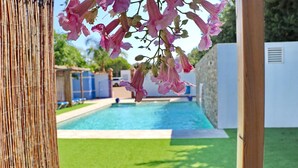 En swimmingpool med fri utsikt över det omgivande området, inklusive ett bambustaket och en gräsyta.