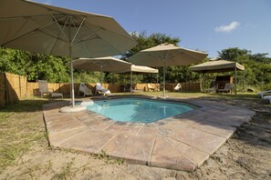 Una piscina al aire libre, sombrillas, sillones reclinables de piscina
