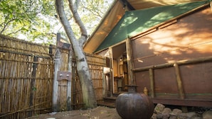 A traditional Japanese building with a bamboo fence, a large metal pot, and a stone pathway.