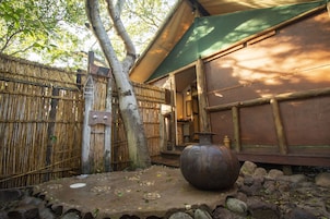 Um edifício japonês tradicional com cerca de bambu, uma panela de metal grande e um caminho de pedras.