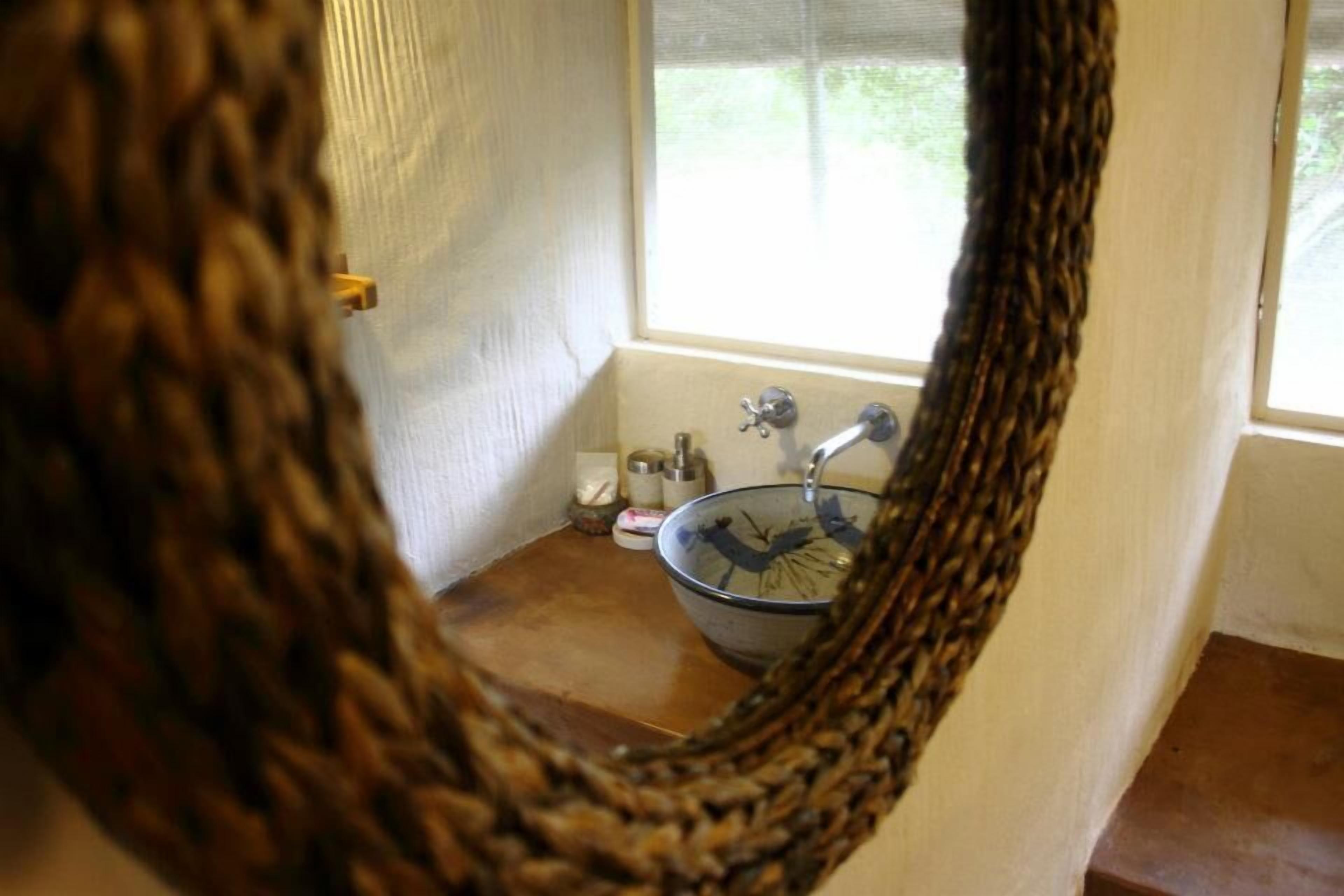 Een badkamer met een wastafel, raam en een gevlochten mand.