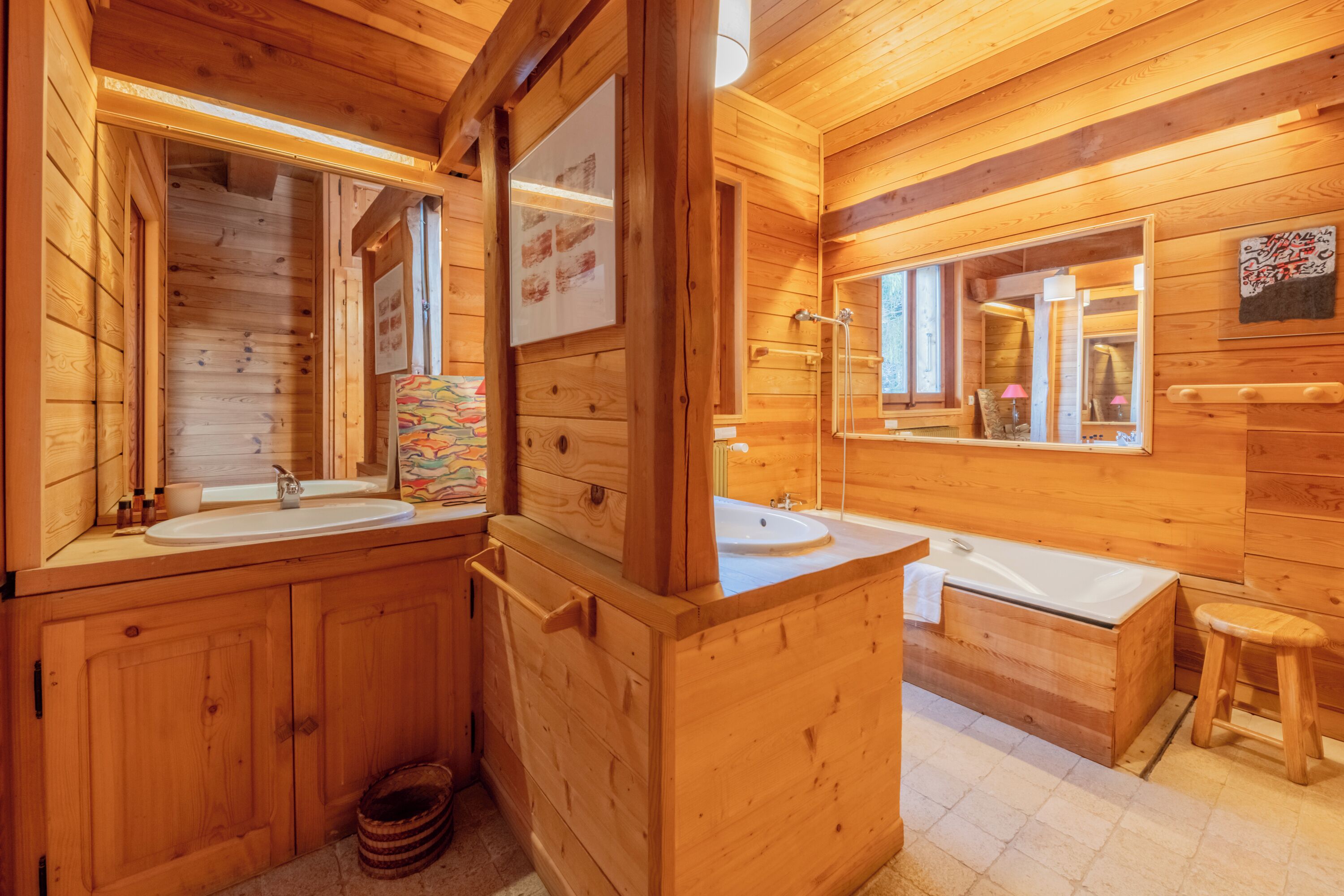 A wooden cabin bathroom with two sinks, a bathtub, and a wooden vanity.