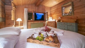 Een houten slaapkamer met een bed, een ontbijttafel, een televisie en een dressoir.