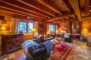 L’intérieur d’un chalet confortable, avec des murs en rondins, un canapé en cuir, une table basse en bois et une cheminée.