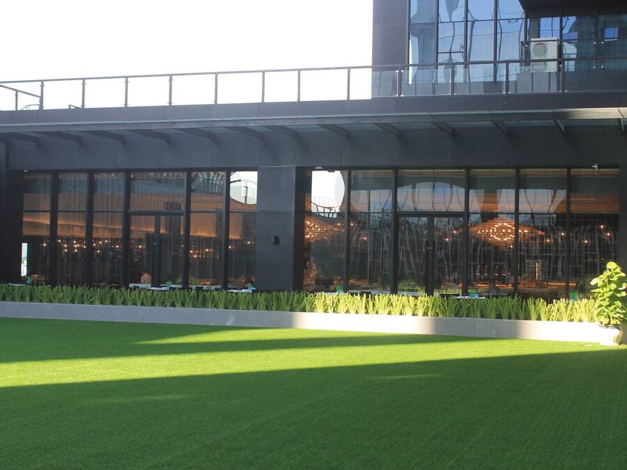 A modern building with large glass windows, a flat roof, and a green lawn in front.