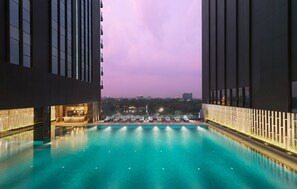 Piscina infinita no terraço com vista para o horizonte urbano ao entardecer.