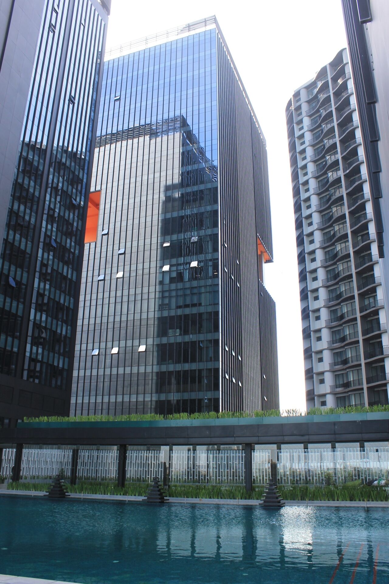 Un moderno edificio de gran altura con ventanas de vidrio reflectante y una señalización naranja visible.