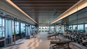 Una palestra moderna con macchinari cardio, panche per pesi e manubri.