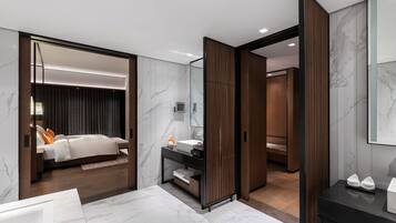 A modern hotel room with a large bed, a vanity with a mirror, and a separate bathroom area.