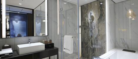 A modern bathroom with a large mirror, a white sink, a black vanity, a glass shower enclosure, and a white bathtub.