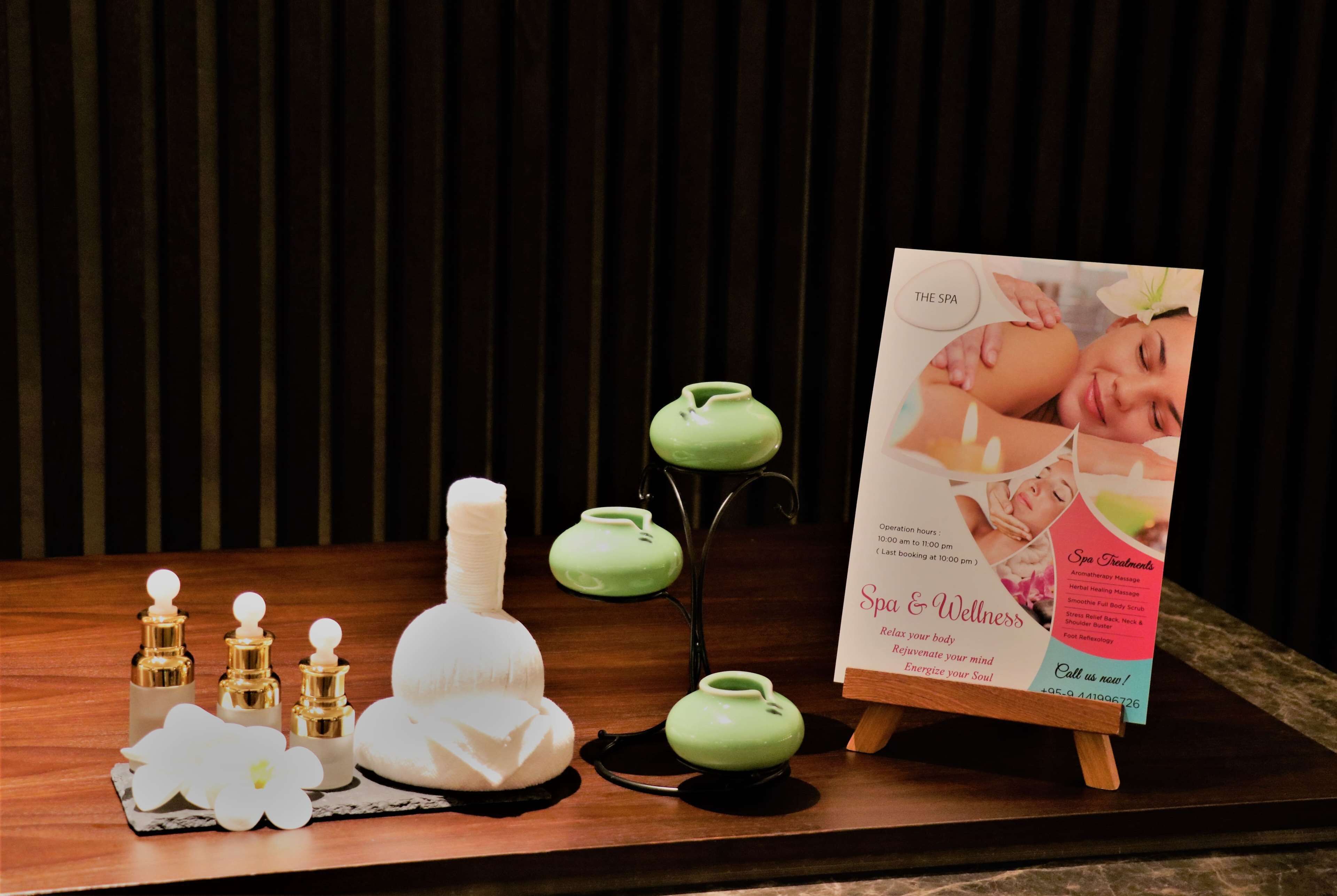 A spa-themed display with a brochure, candles, and small bottles on a wooden table.