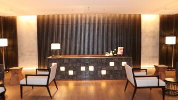 A reception area with a stone counter, two chairs, and a wooden floor.