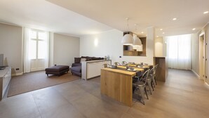 Ein modernes Wohnzimmer mit einem Holzesstisch, einer Couch und einer Küchenzeile mit integrierter Kochinsel.