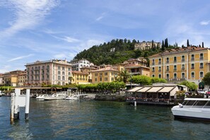 Enjoy waterfront views from the balcony of this serene retreat, surrounded by lush greenery and a hill with buildings.