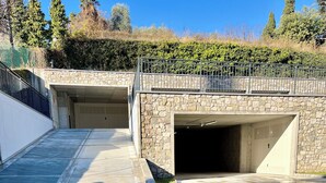 Eine Parkgarage mit zwei freien Stellplätzen, einer Steinmauer und einem Metallgeländer.