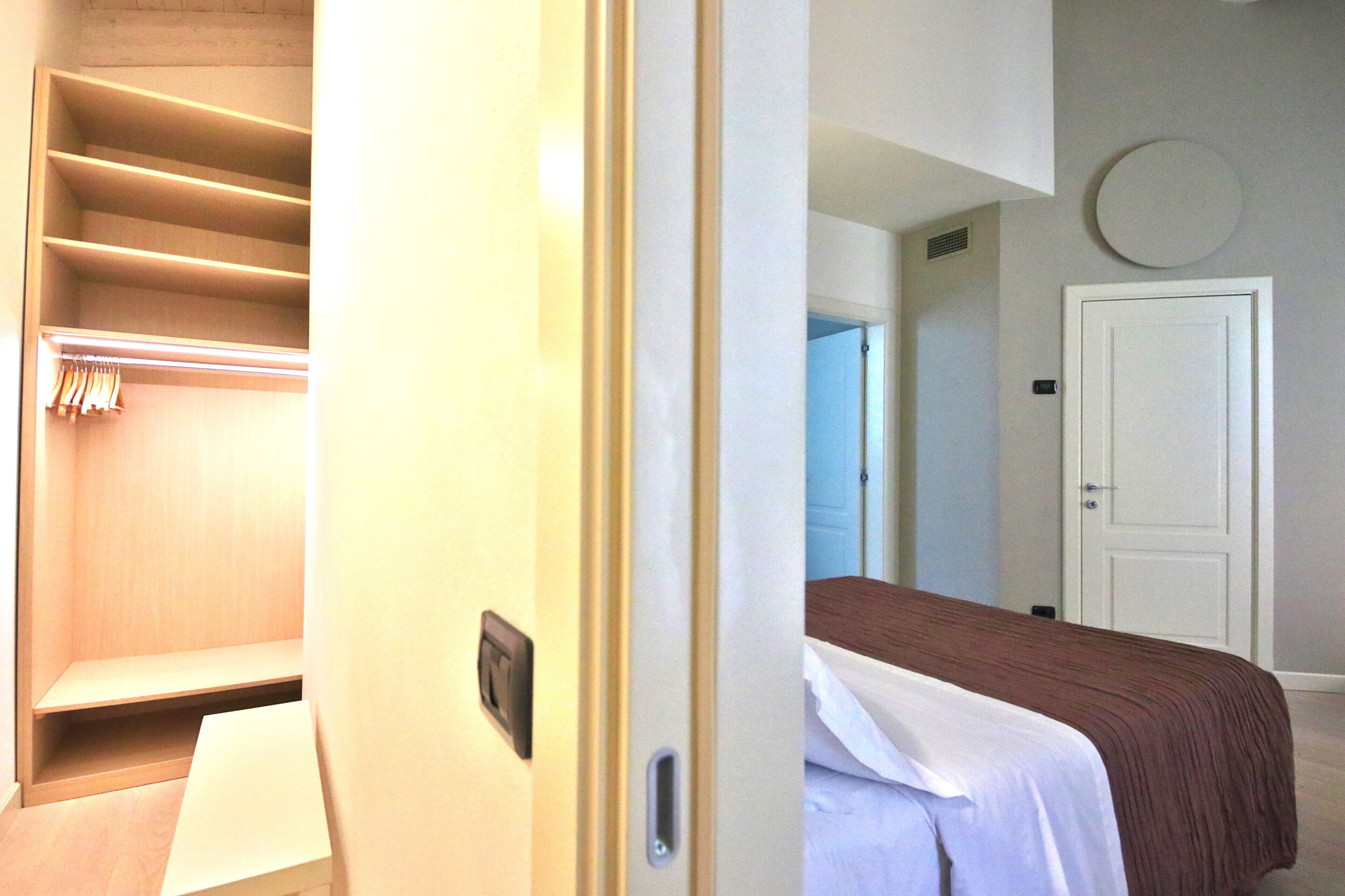 Une chambre d’hôtel comprenant un lit, une armoire et une porte donnant sur une autre pièce.