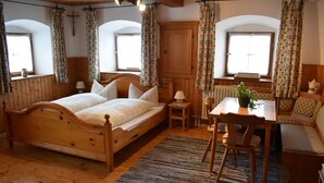 A cozy bedroom with a wooden bed, a small table with a plant, and a bench. - Ferienwohnung "In der Stube"  (28qm) (Kiefersfelden)