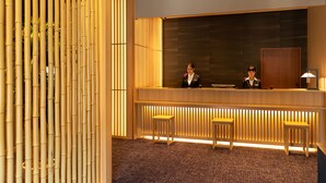 A reception area with a wooden reception desk, two wooden stools, and a bamboo wall.