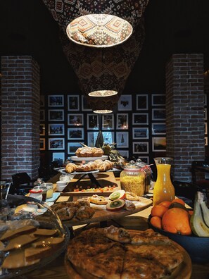 A buffet with various food items, a fruit bowl, and a juice pitcher.
