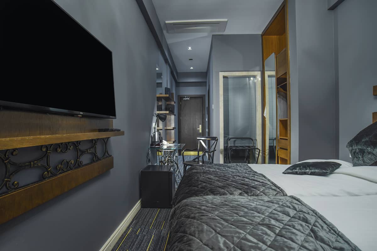 Een hotelkamer met een bed, een aan de muur bevestigde televisie, een bureau met stoel, en een kledingkast.