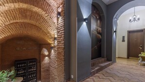 Un pasillo con un arco de ladrillo, una alacena para vinos y una araña.
