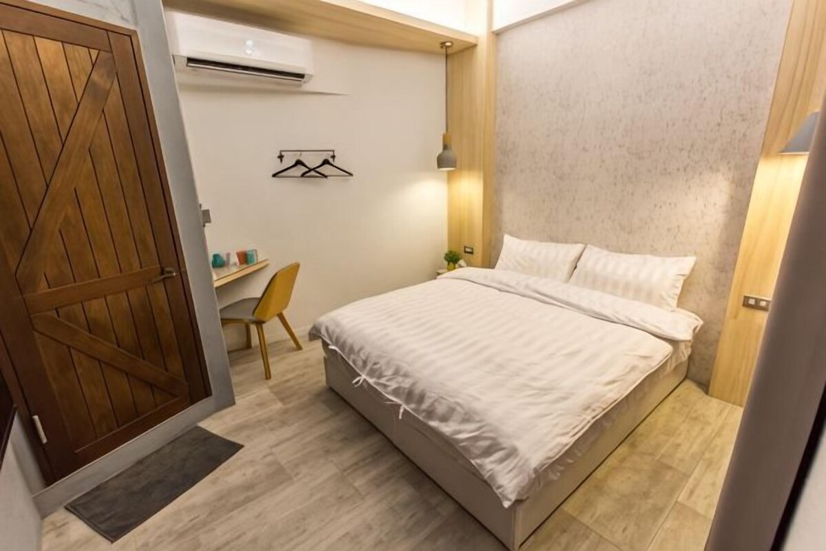 A bedroom with a bed, a desk, and a chair.