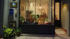 Fachada con puerta de vidrio grande, plantas en macetas y una lámpara colgante.