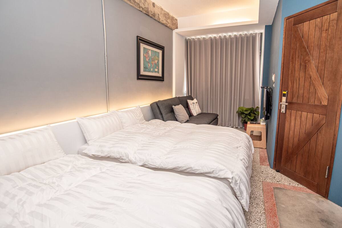 A bedroom with a large bed, a chair, a wooden door, and a framed picture on the wall.