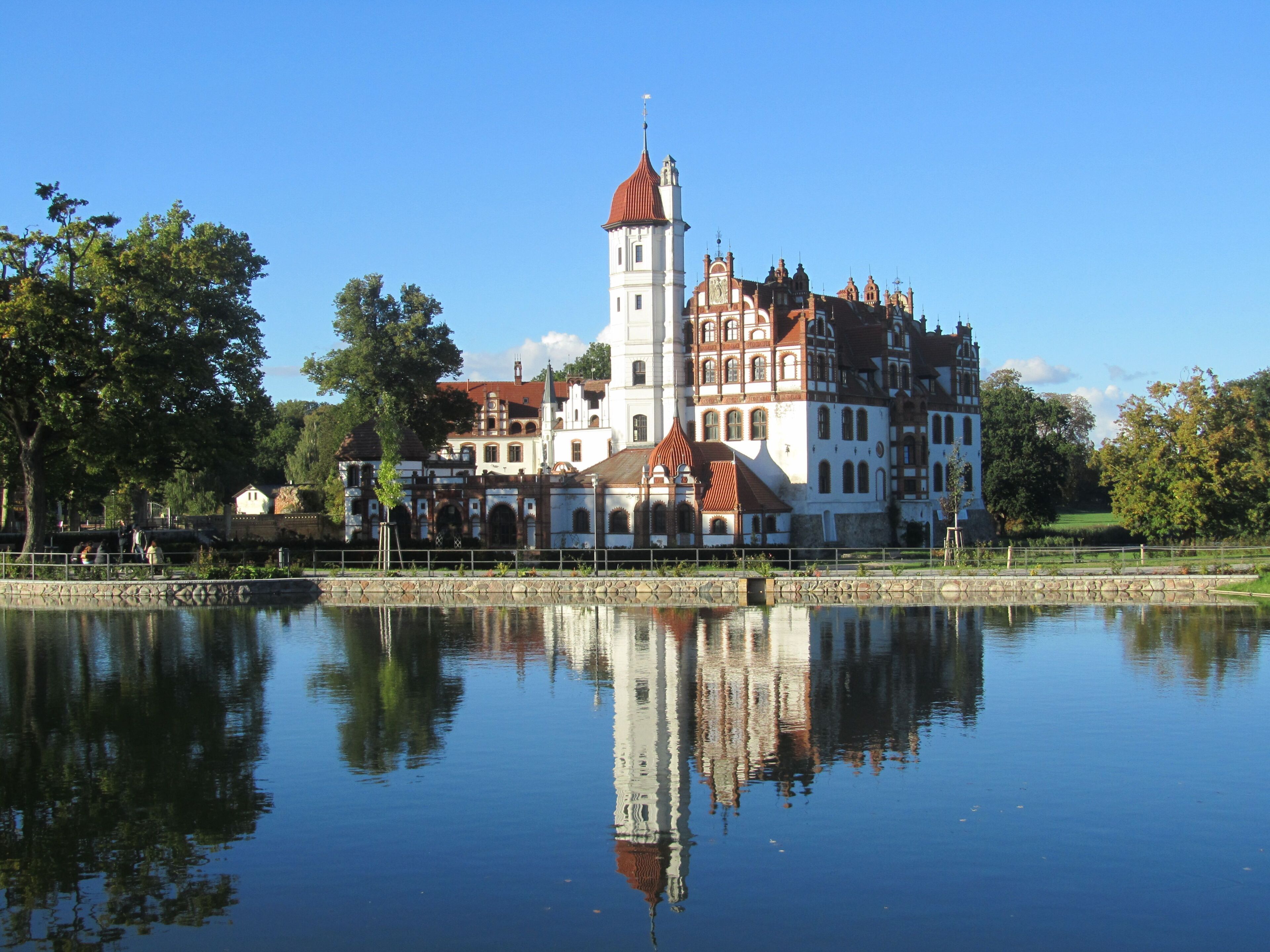 Ein historisches Gebäude mit einem markanten Turm, der sich in ruhigem Wasser spiegelt.